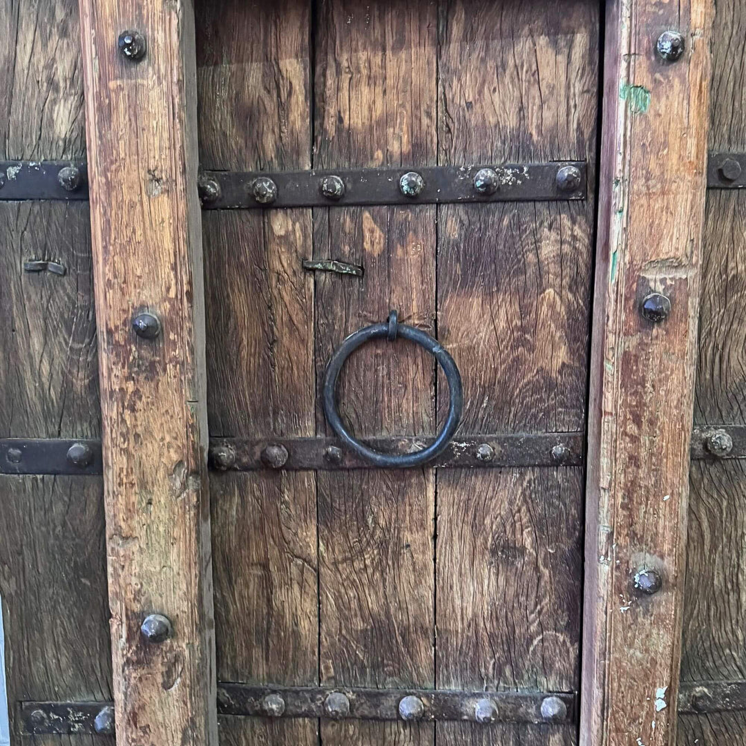 Close-up of the Castle Door showing a traditional metal ring handle framed by carved wood and studs