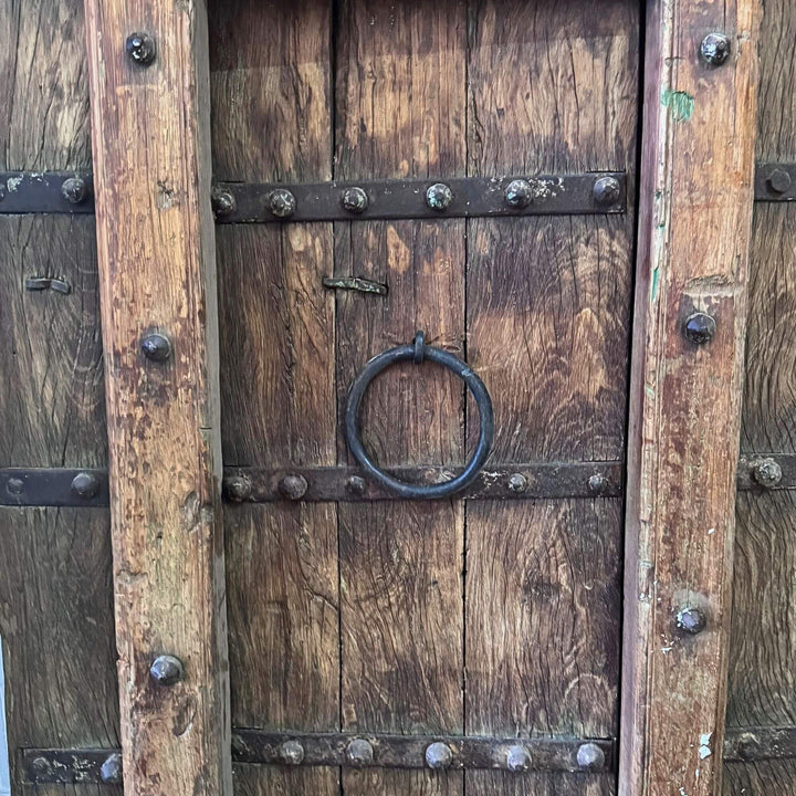 Close-up of the Castle Door showing a traditional metal ring handle framed by carved wood and studs