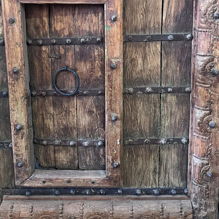 Detail of the smaller integrated Castle Door with carved frame, metal straps, and ring pull