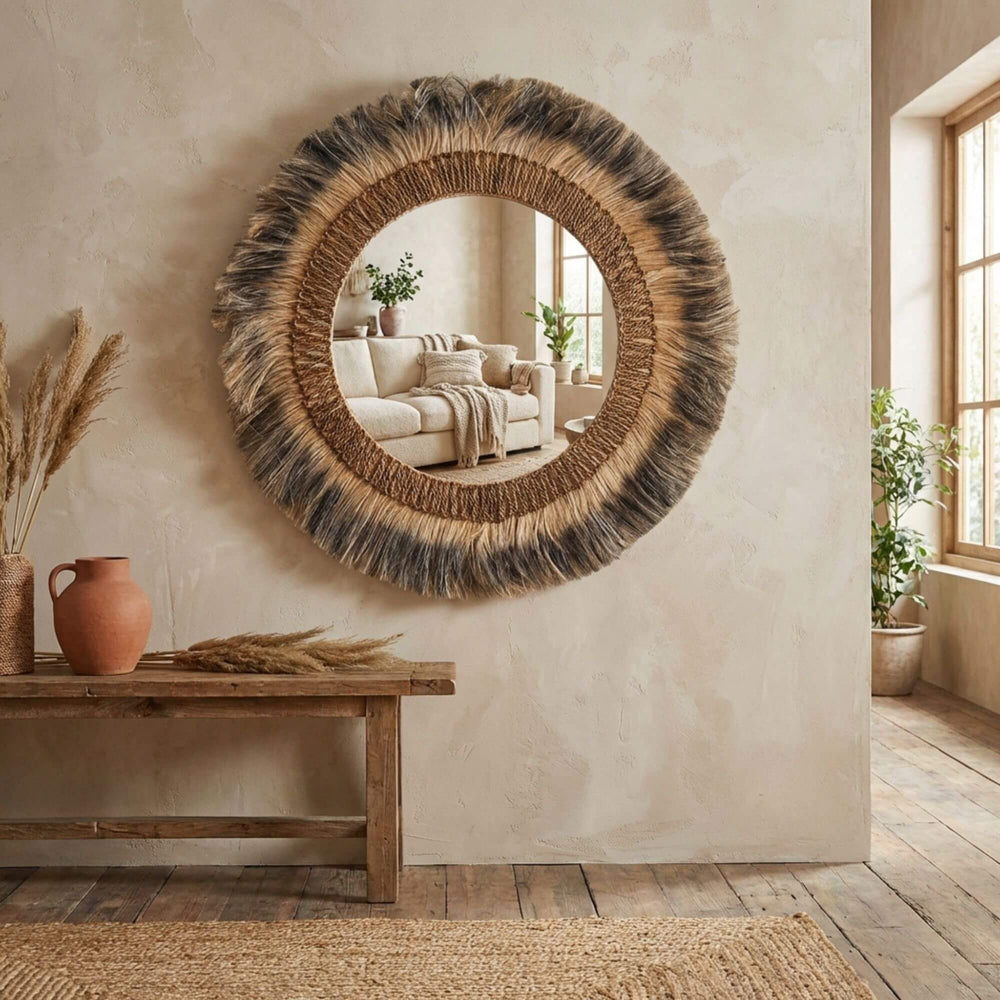Round woven Cendana mirror on a wall with a wooden bench and decor items in a room.