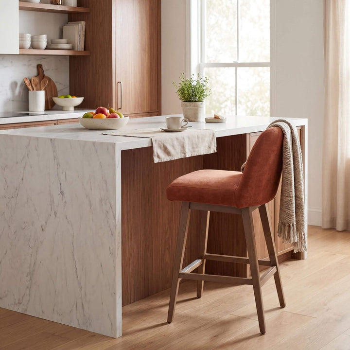 Styled kitchen setting featuring the Cord Gracia bar stool beside a marble island in a warm natural interior.