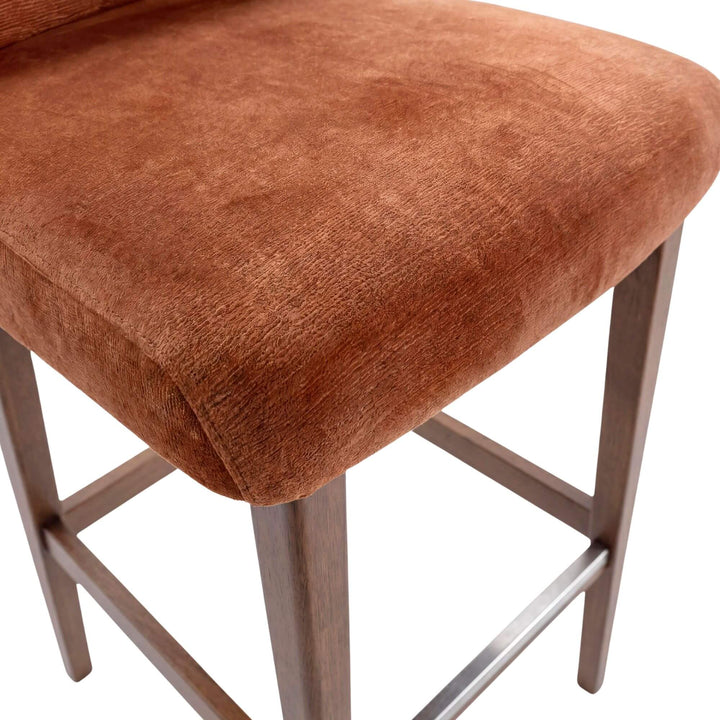 Close-up detail of the upholstered seat and wood leg structure showing the warm fabric texture.