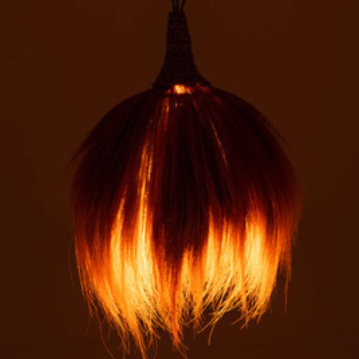 Coza Lamp illuminated, casting a warm ambient glow through natural fibers.
