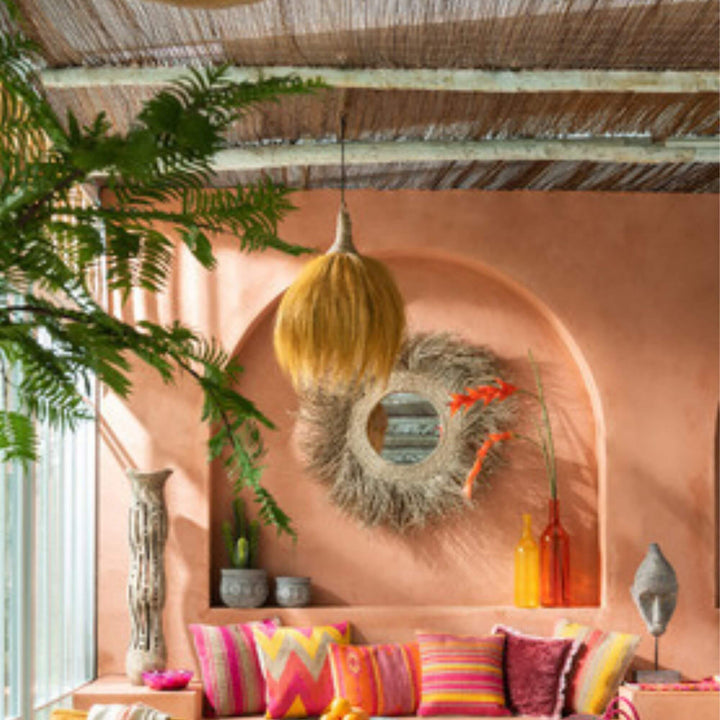 Coza seagrass pendant styled in a tropical interior above a dining setting.