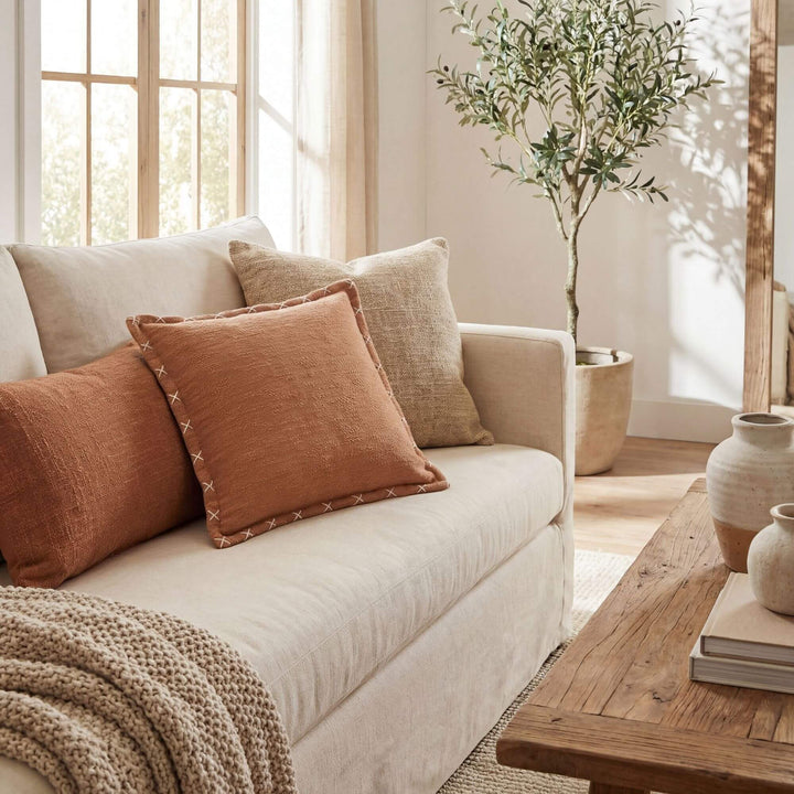 Styled interior setting featuring the terracotta Crosswave cushion on a sofa with soft neutral textiles.