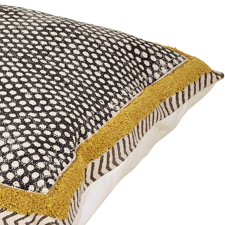 Dhara cushion close-up with black dot pattern, mustard textured border, and herringbone side detail