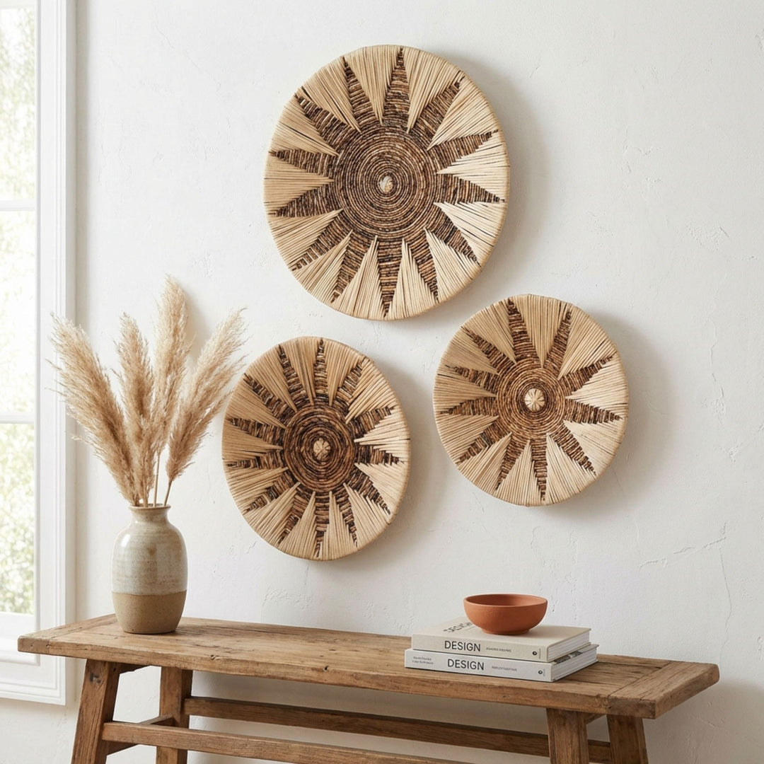 Three woven Diani wall deco plates on a white wall above a wooden console table with decor items.