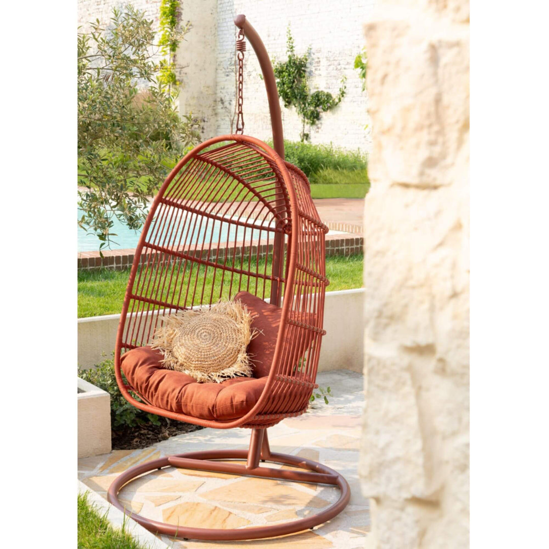 Terracotta hanging chair styled outdoors beside a pool