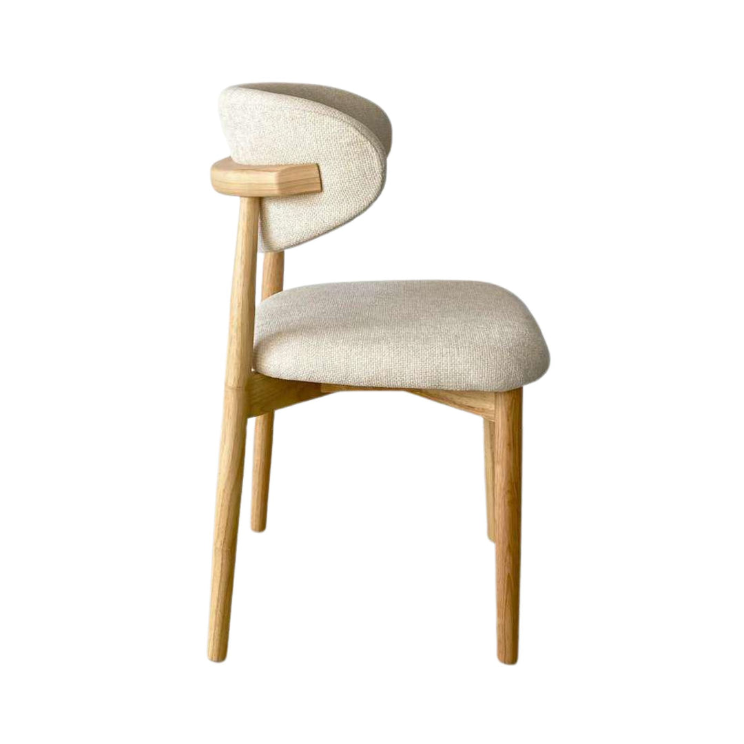 Side view of the chair highlighting its rounded silhouette, upholstered seat, and clean wooden frame.