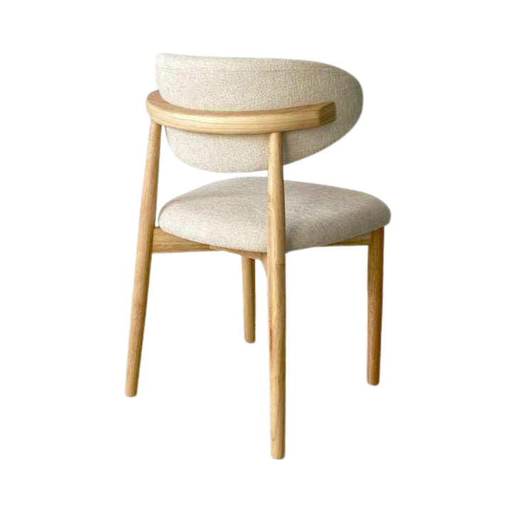 Rear angled view of the Elara dining chair showing the curved backrest and natural rubberwood structure.