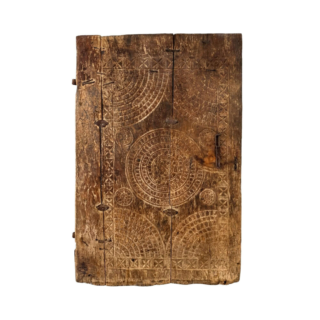 Front view of the Eufrates antique reclaimed wood door with carved patterns and metal details.