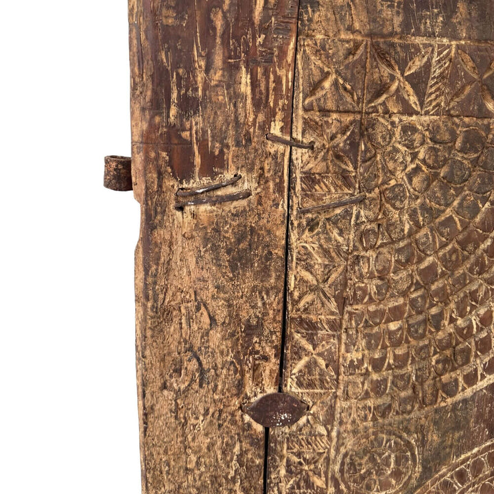 Close-up detail of the carved wood surface with aged patina and texture.