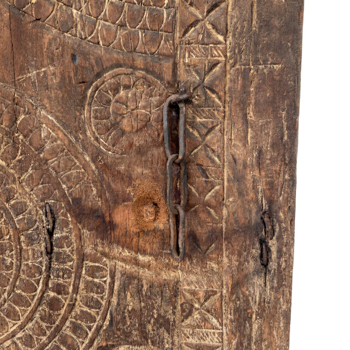Close-up detail of the carved wood surface with aged patina and texture.