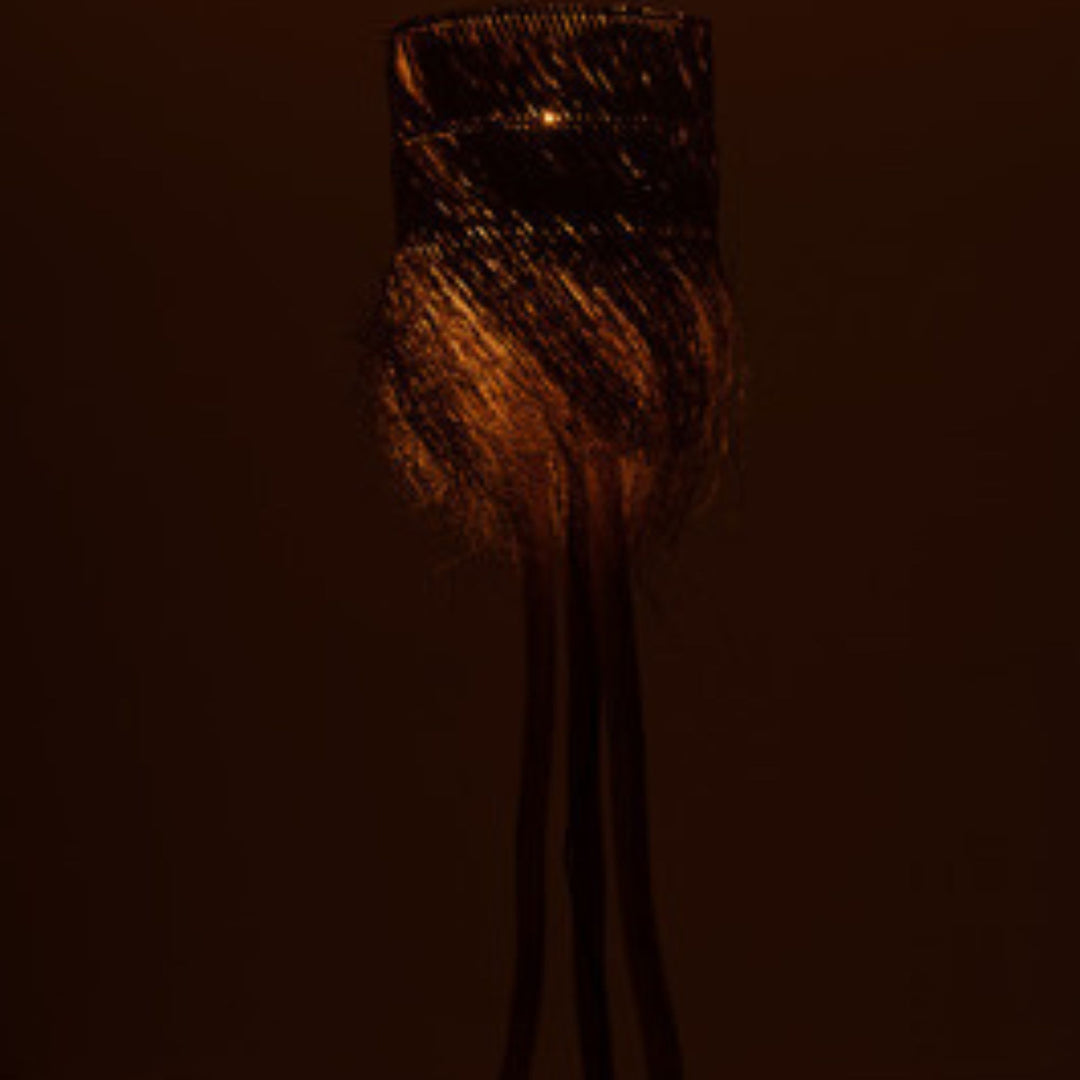 Fury floor lamp illuminated, casting warm textured light in a room.