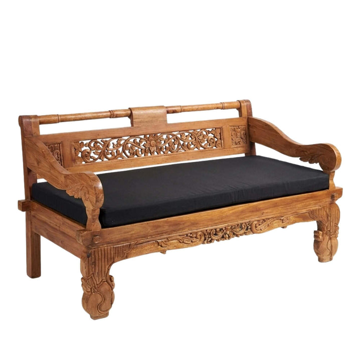 Angled view of Govinda Indonesian carved teak wood daybed highlighting its detailed carved backrest and armrests.