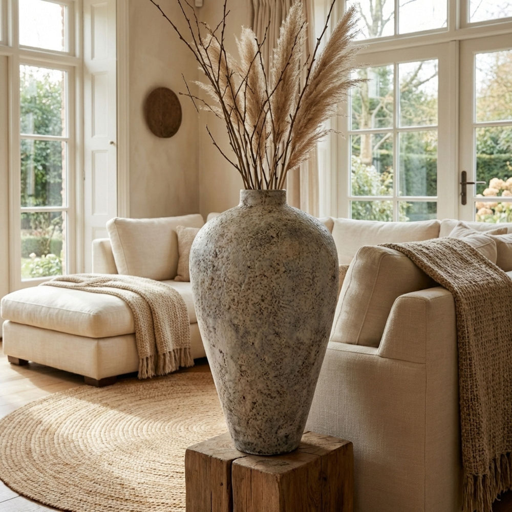 Styled interior setting featuring the grey antique vase placed in a living room with dried branches.