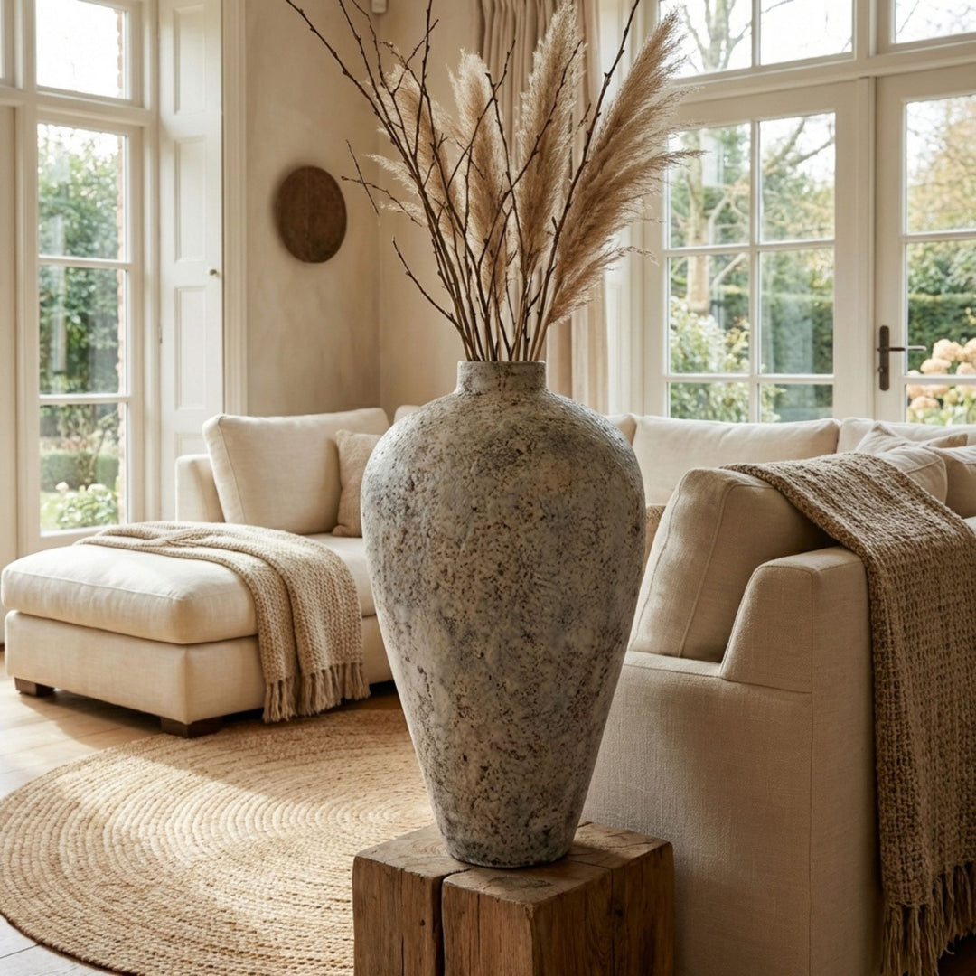 Styled interior setting featuring the grey antique vase placed in a living room with dried branches.