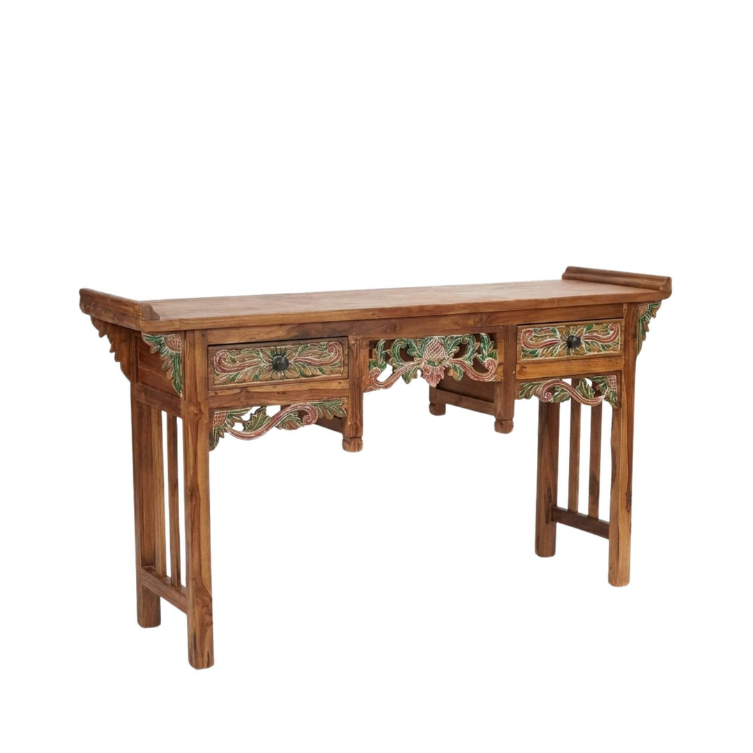 Angled view of Gunnar carved teak wood console table showcasing its detailed carved apron.