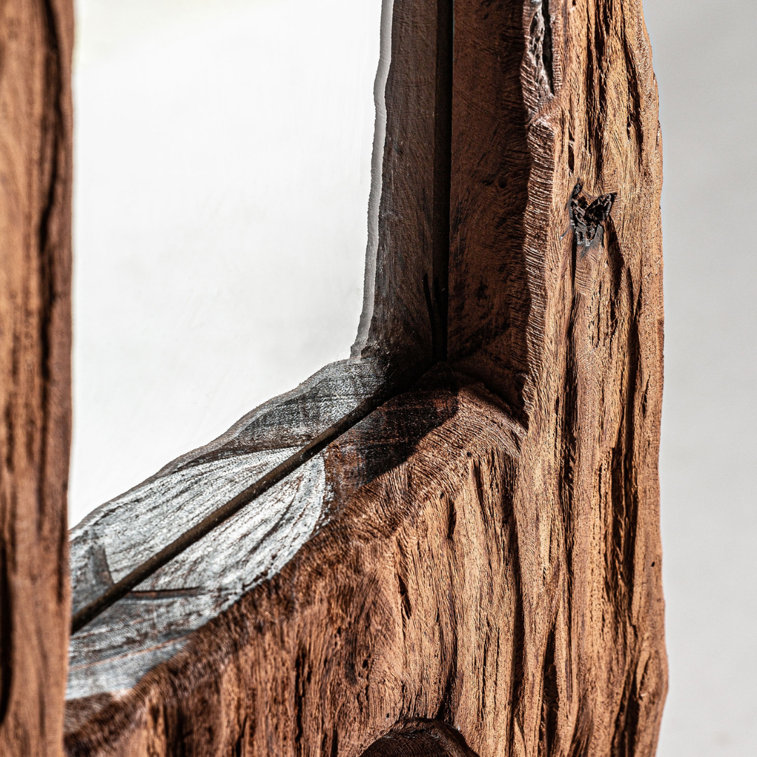 Detail view of the teak wood base and mirror edge showing raw organic character.
