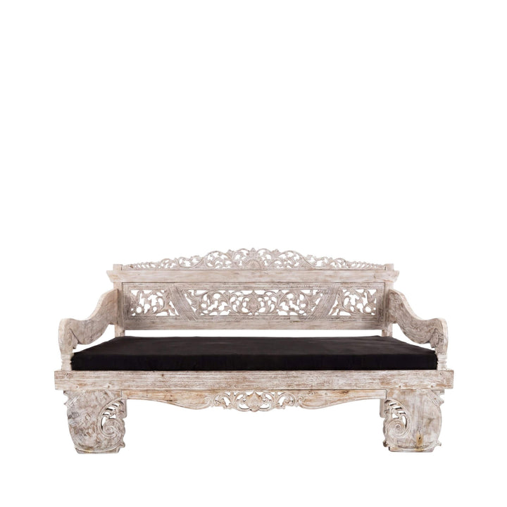 Front view of the Hela Indonesian carved teak wood daybed showing its ornate frame and dark seat cushion.