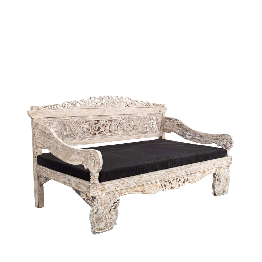 Front angled view of the daybed highlighting its carved arms, decorative backrest, and solid teak structure.