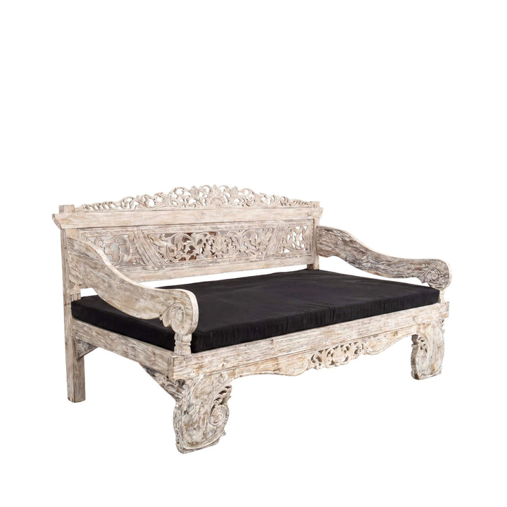 Front angled view of the daybed highlighting its carved arms, decorative backrest, and solid teak structure.