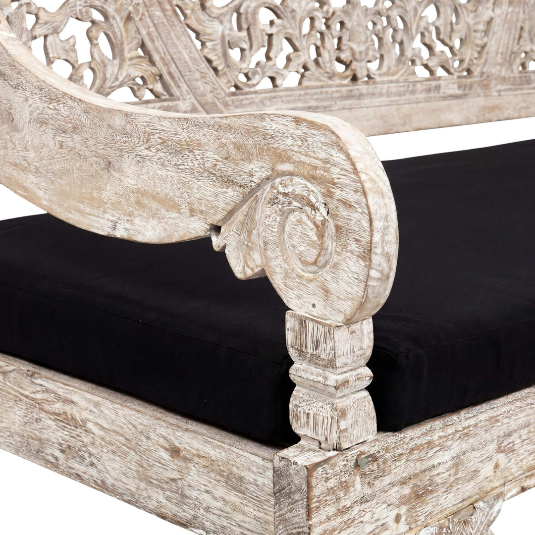 Close-up detail of the armrest and cushion showing the carved wood texture and upholstered seat.