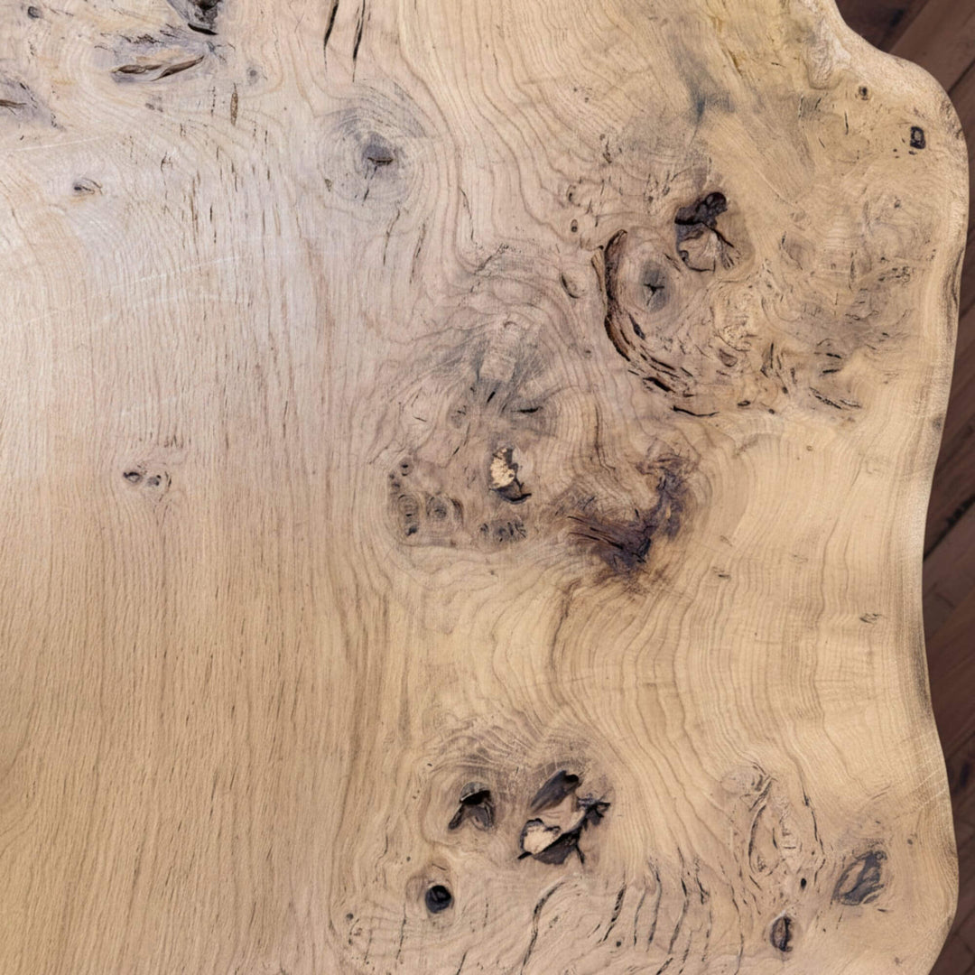 Close-up of the oak wood grain and natural knots on the Hera table surface.