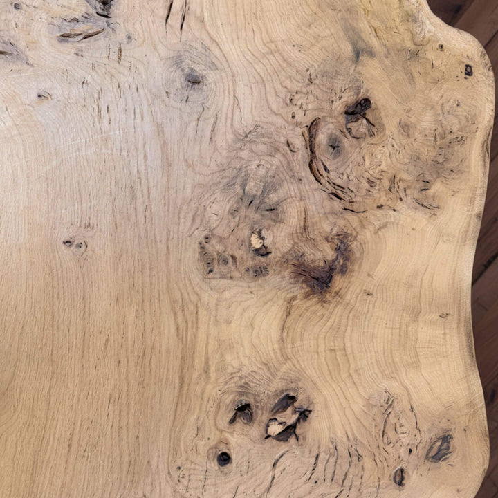 Close-up of the oak wood grain and natural knots on the Hera table surface.