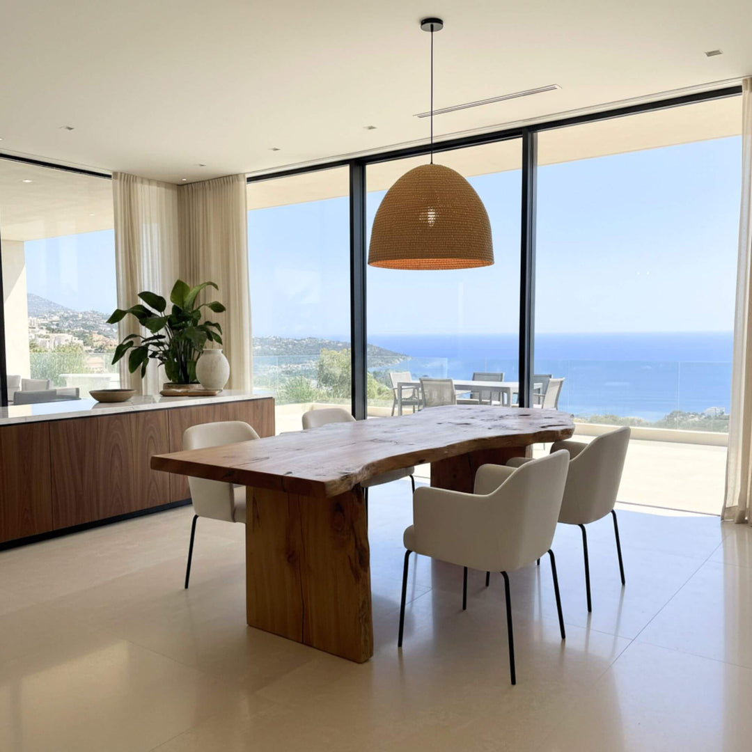 Modern dining area with a Hera Dining table and white chairs, featuring large windows with a view of the ocean.