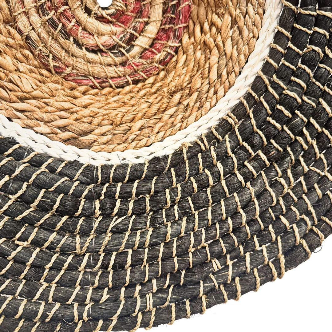 Close-up of Harum Wall Deco, handwoven from abaca, rattan, and cotton in a natural and black circular design.