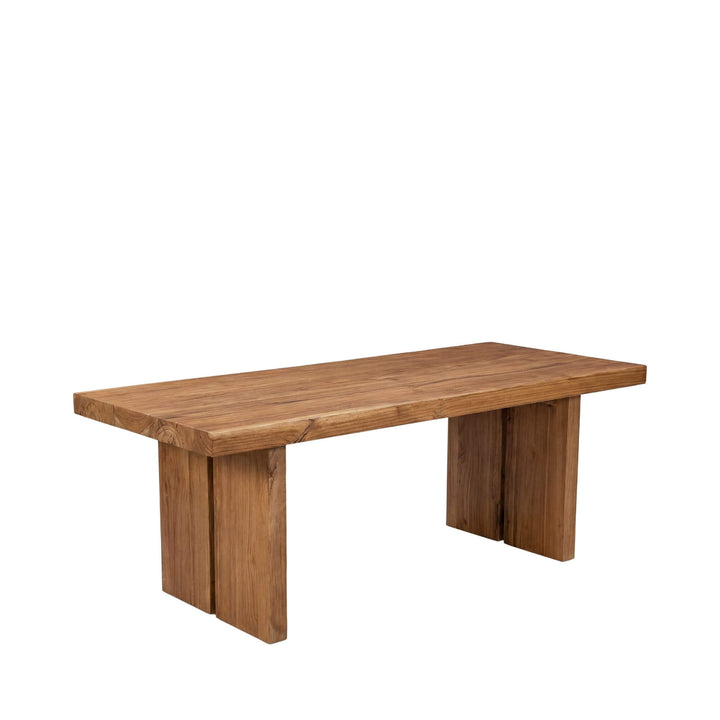 Front view of the Indonesian teak dining table showing its solid wood top and sculptural base.
