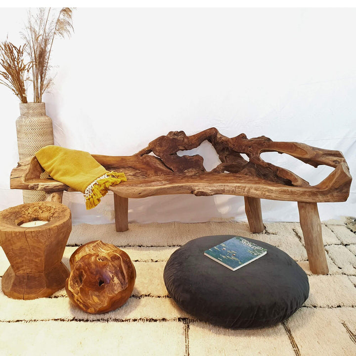 ISHA TEAK ROOT WOOD BENCH with natural patterns, yellow cushion, and black pillow on a light-colored floor.
