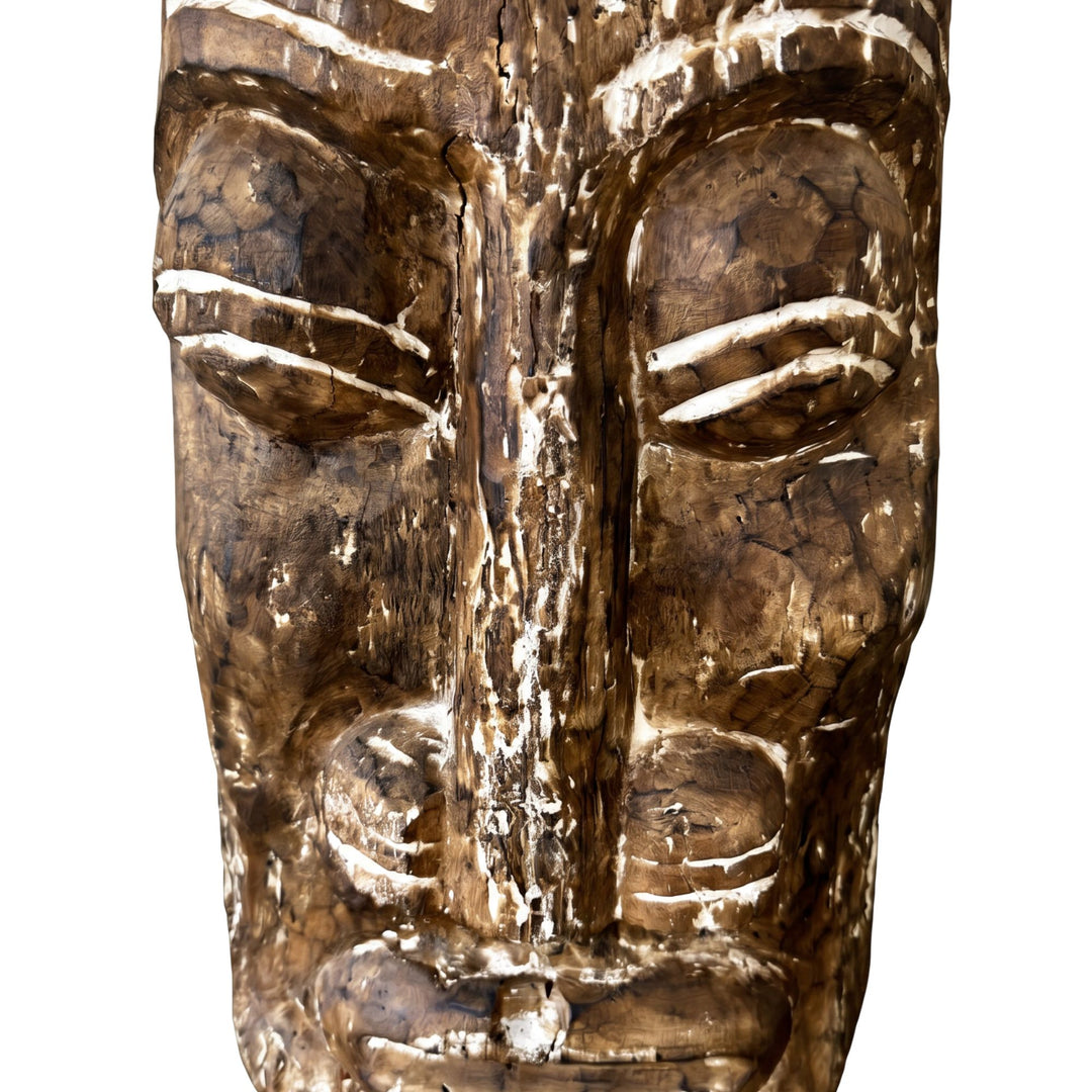 Close-up detail of the carved face showing the aged wood texture and tribal-inspired patterning.
