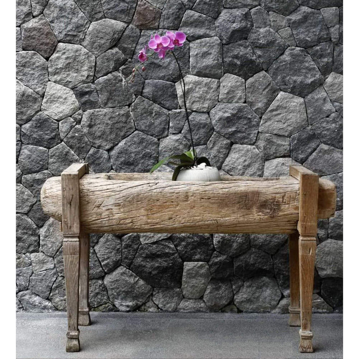 Front view of reclaimed teak wood planter with orchid placed on top against stone wall