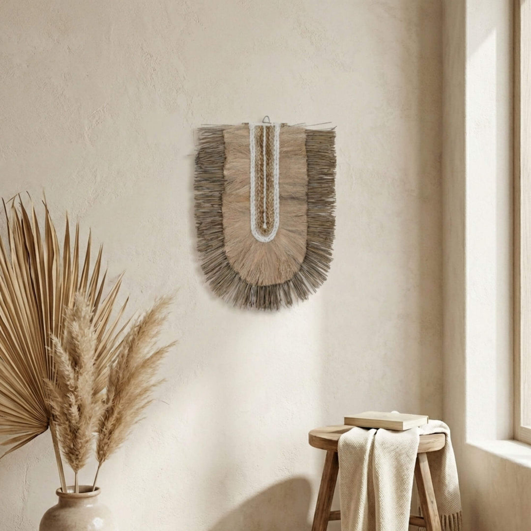 Kalalao wall art piece on a neutral wall with a vase of dried plants and a wooden stool.