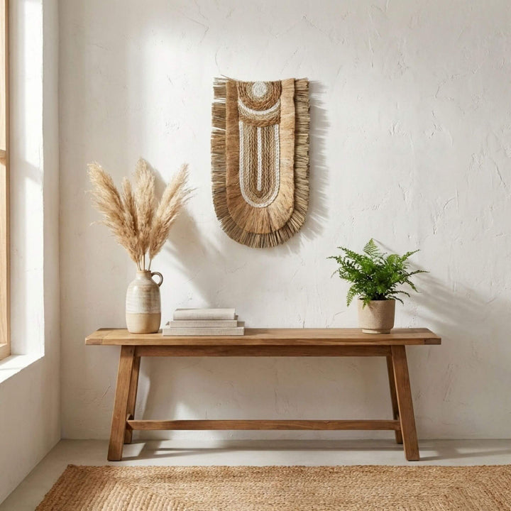 Nest living room with wooden bench, decorative Kalalao wall hanging, and plants.