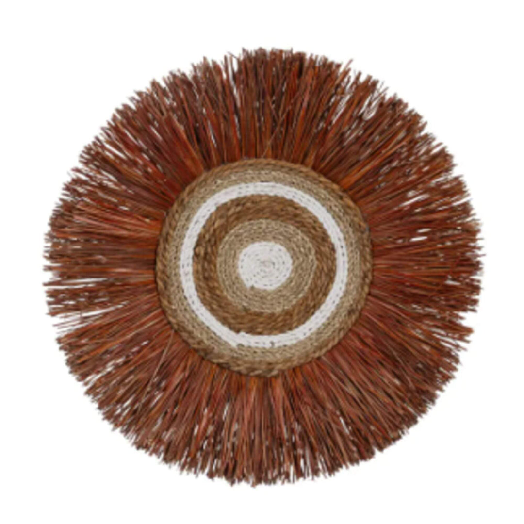 Handwoven rattan and natural fiber wall art in warm brown and red tones.

