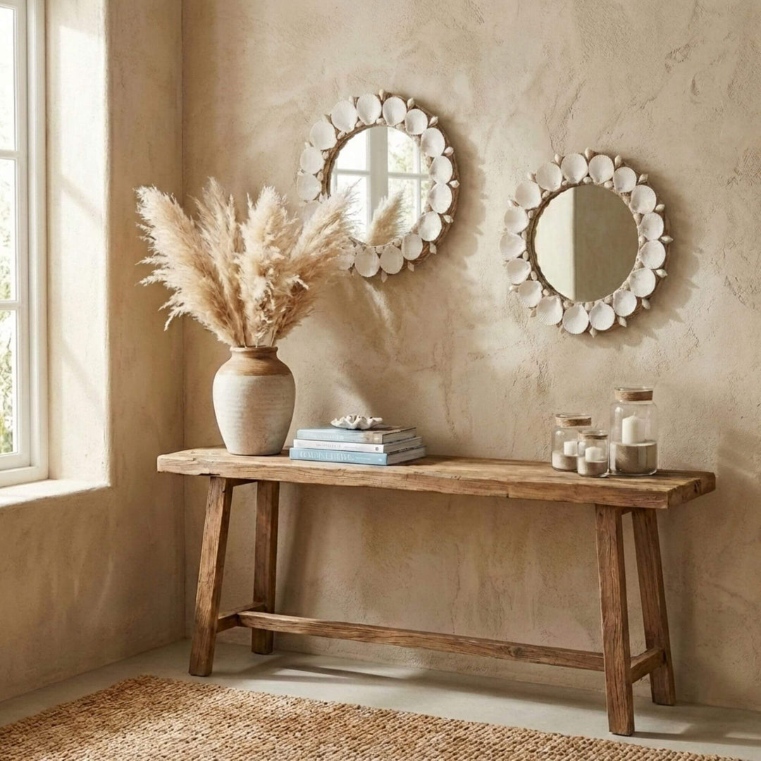Wooden bench with decorative items against a beige wall with two Kerang round mirrors.