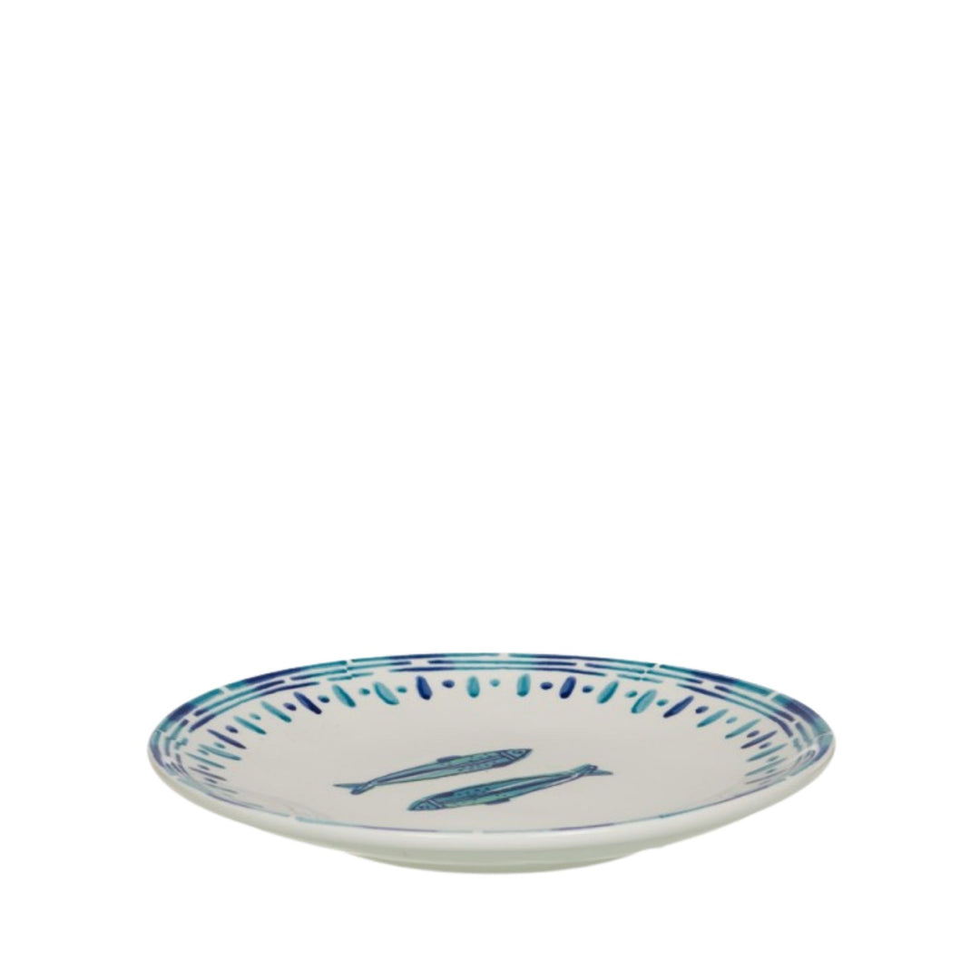 Angled side view of a Kyanos ceramic plate with blue fish illustration and striped border