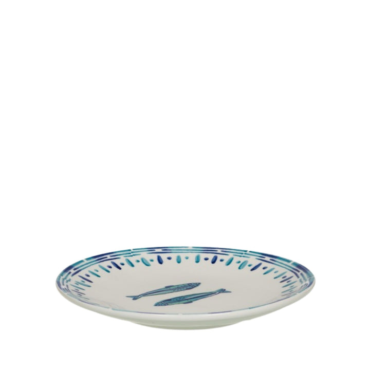 Angled side view of a Kyanos ceramic plate with blue fish illustration and striped border