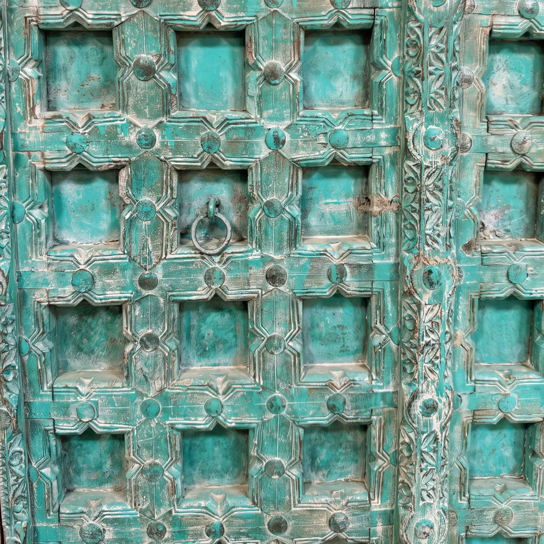 Close-up of the Lakshimi wardrobe highlighting the distressed turquoise carving and detailed geometric door panels