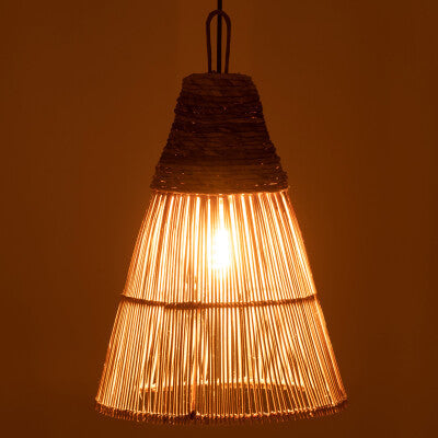 Liba Lamp illuminated, casting warm light through rattan weave