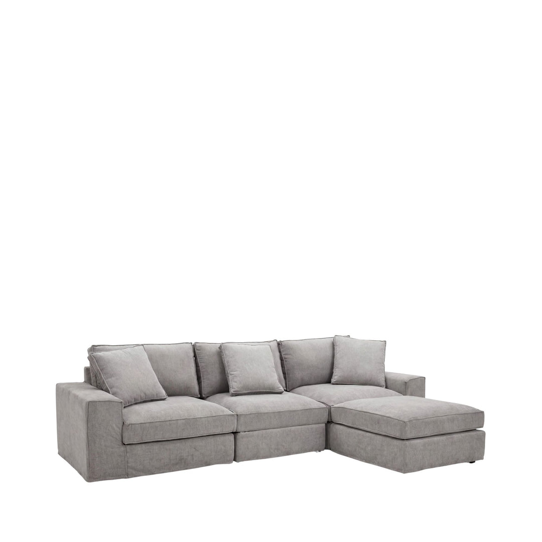 Front view of the Lucca sofa with matching pouf showing its soft neutral upholstery and relaxed proportions.