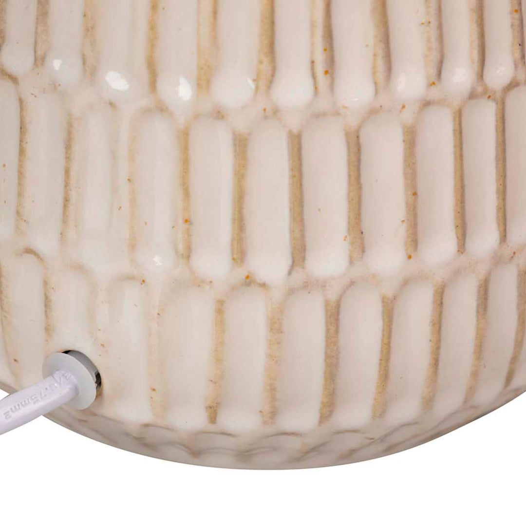 Close-up detail of the soft beige ceramic base showing its rounded ribbed texture.