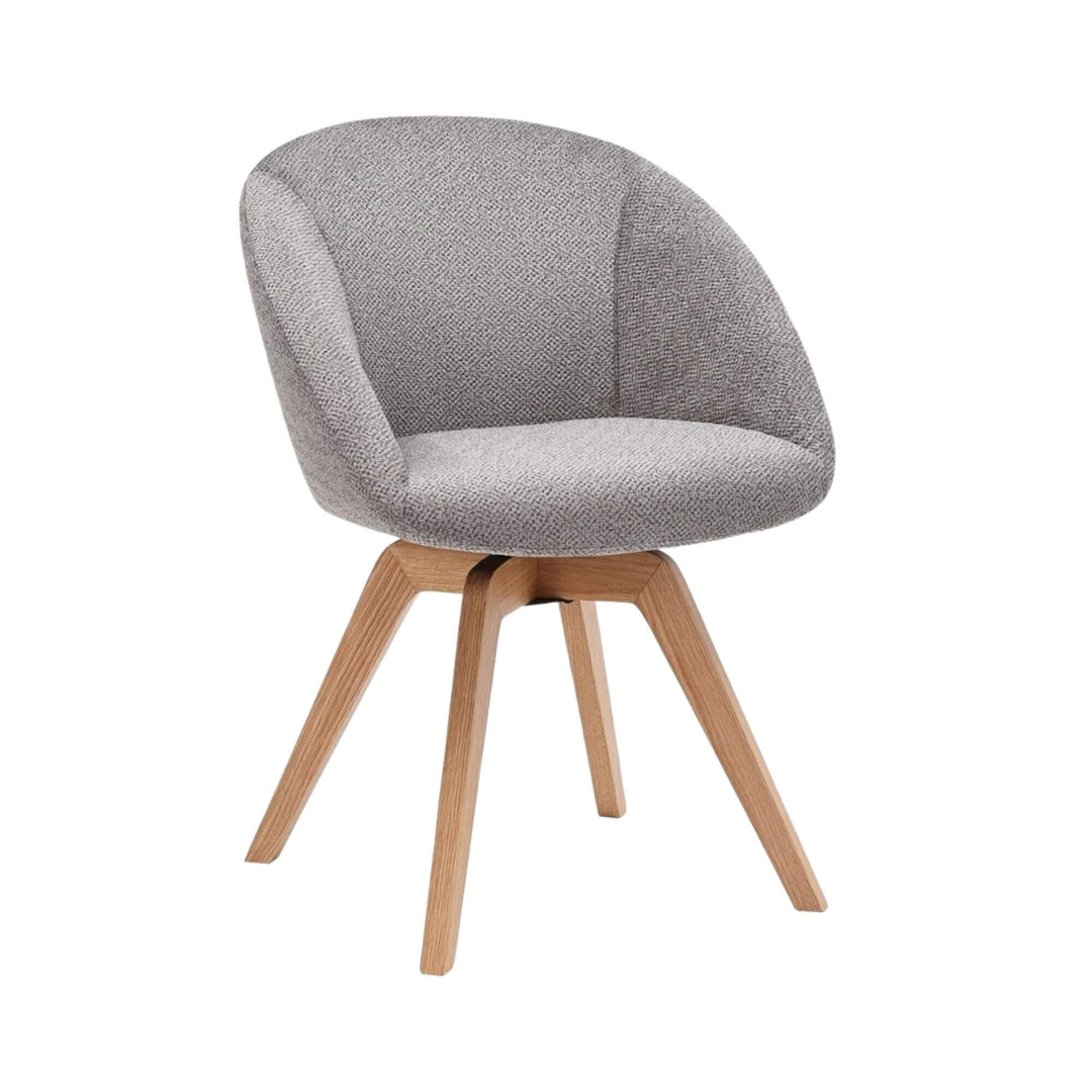 Angled view of the Lume dining chair showing its curved upholstered seat and ash wood legs.