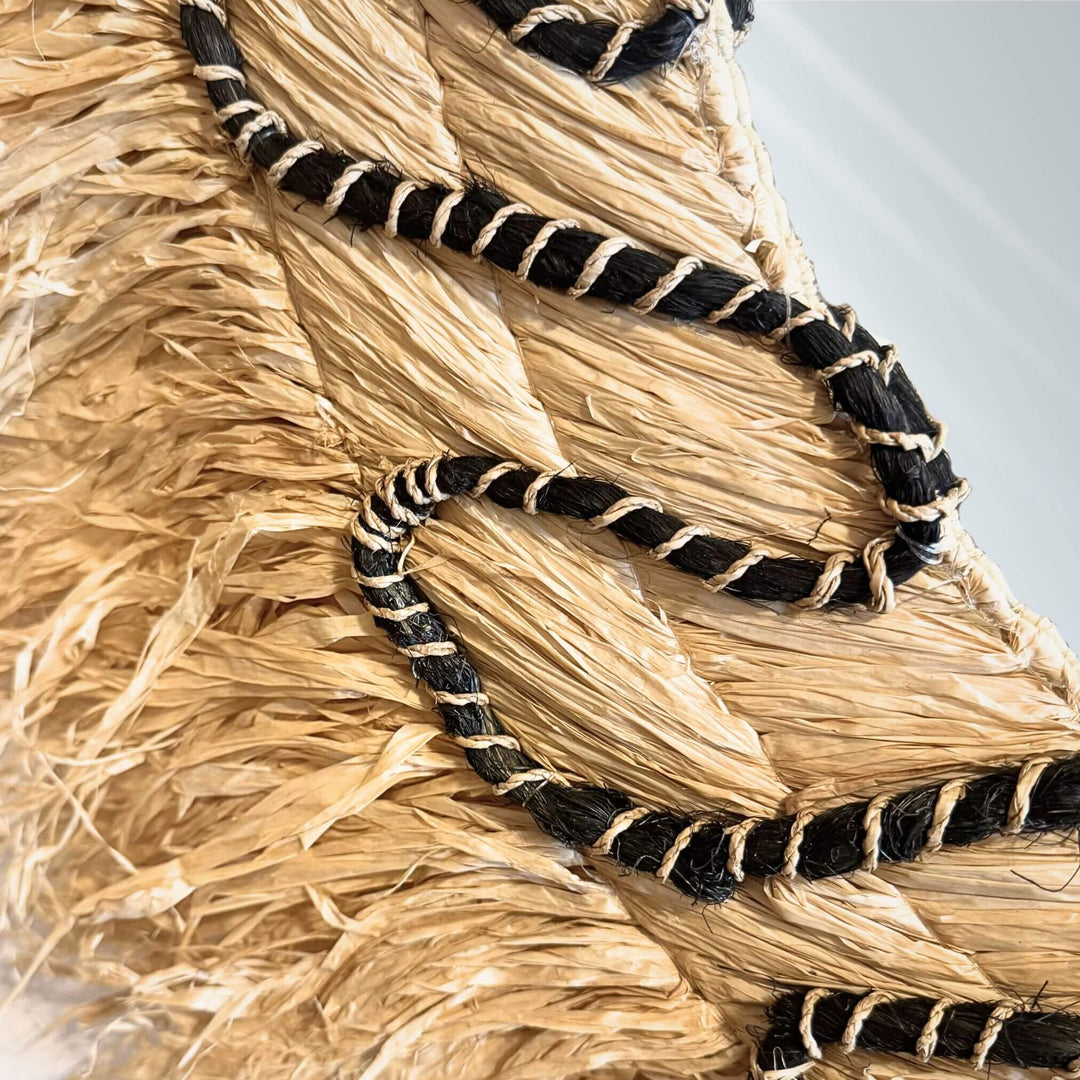 Close-up of Lautan Mirror with teardrop shape, handwoven abaca frame, and black braided accents
