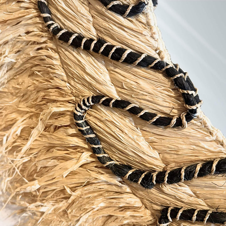 Close-up of Lautan Mirror with teardrop shape, handwoven abaca frame, and black braided accents
