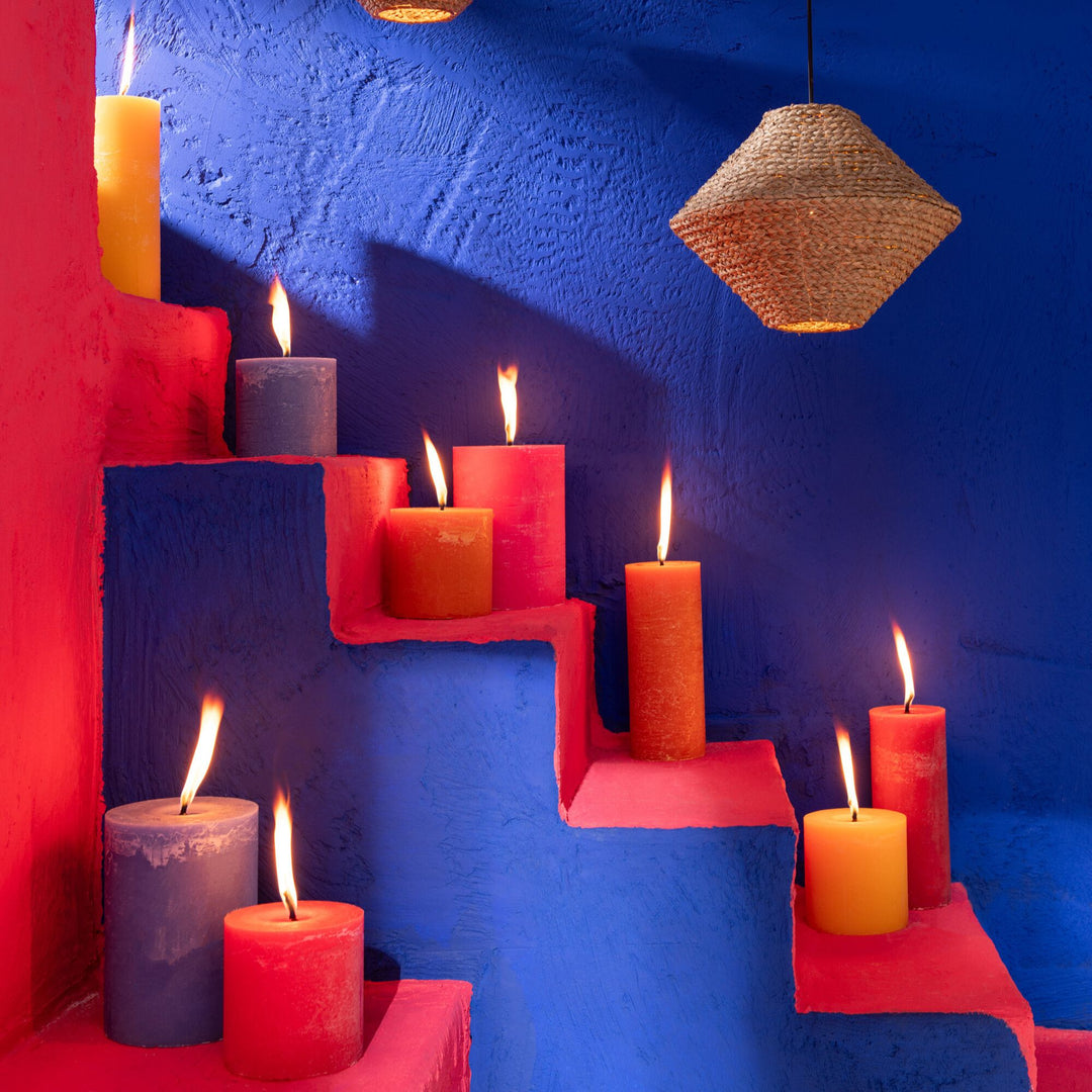 Mahe Red Outdoor Candle styled on colorful outdoor steps.