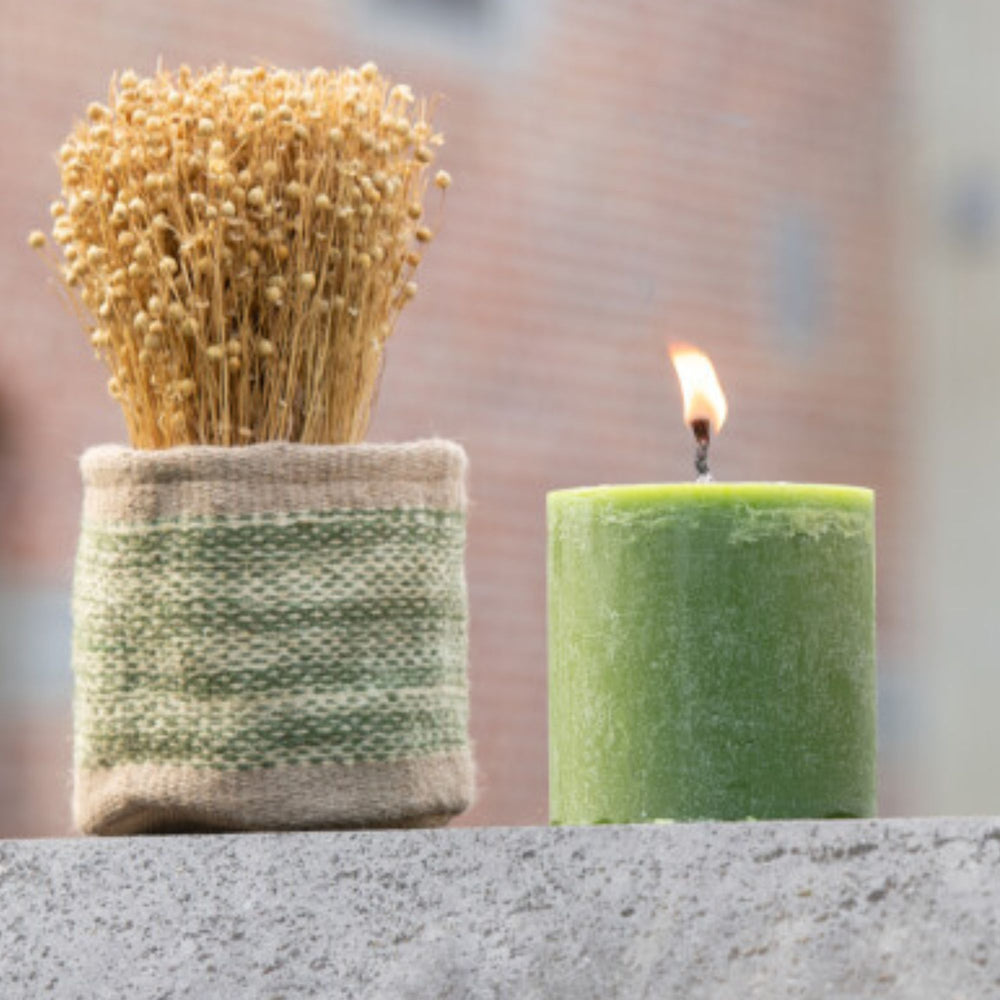 Outdoor scene featuring the Mahé Green Outdoor Candle beside decorative accessories.